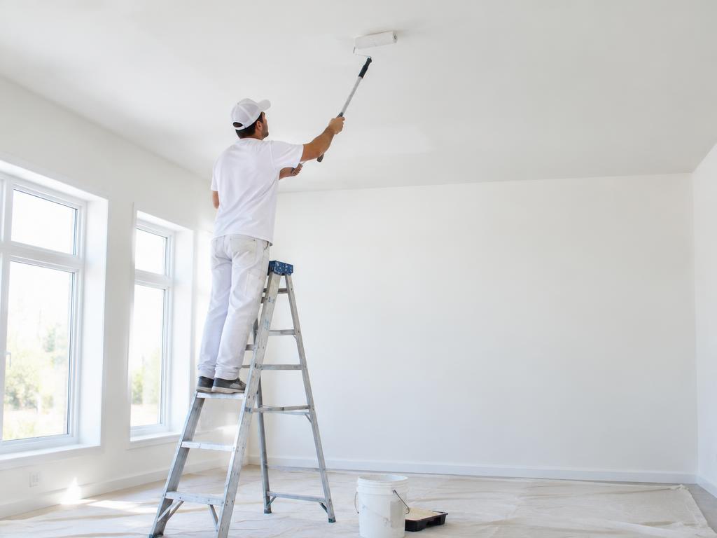 Pintor num escadote a pintar um teto branco